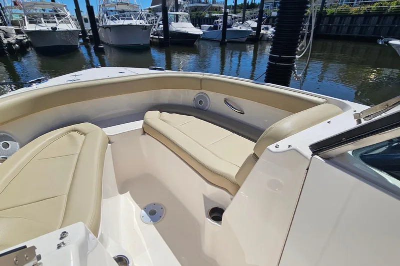 Slide: The Image of 2016 Pursuit DC 265 Dual Console boat interior with beige seating at marina. - 23