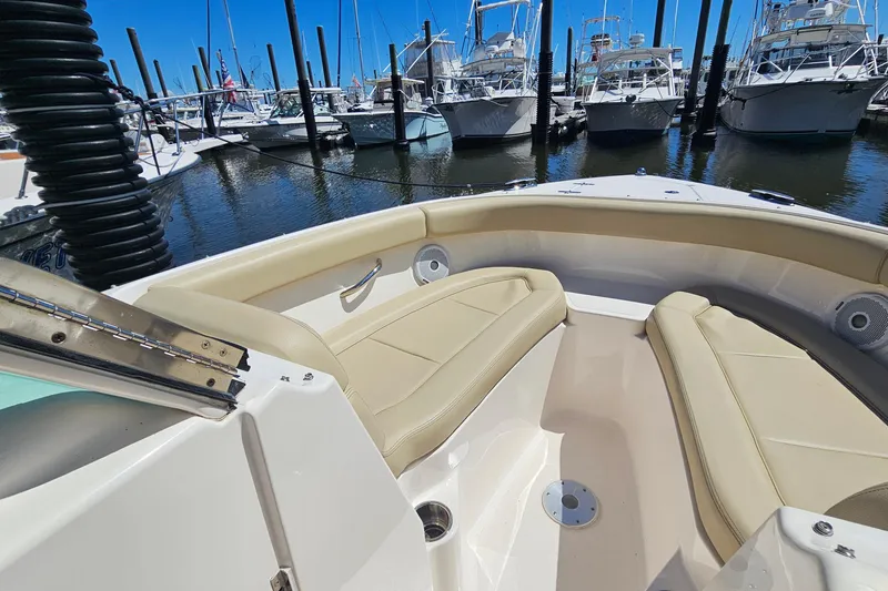 Slide: The Image of 2016 Pursuit DC 265 Dual Console boat interior with beige seating at marina. - 24