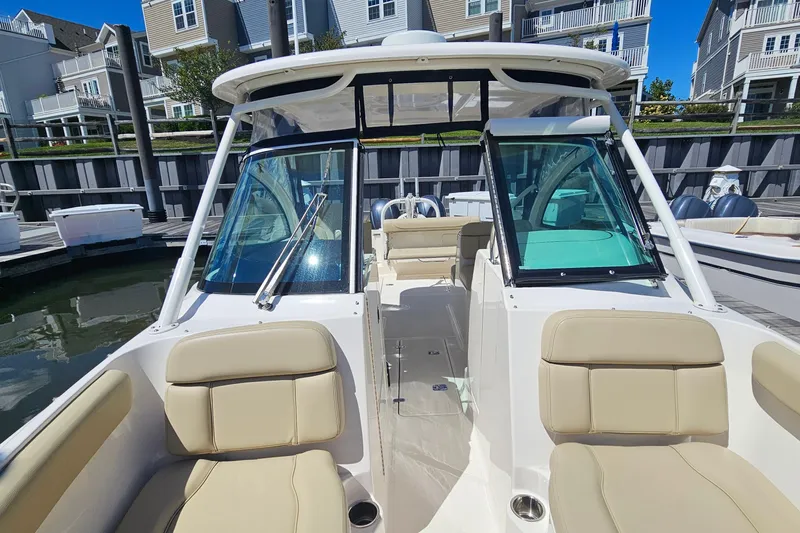 Slide: The Image of 2016 Pursuit DC 265 Dual Console boat with beige seating at a marina. - 25