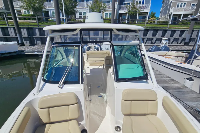 Slide: The Image of 2016 Pursuit DC 265 Dual Console boat docked, featuring beige seating and sleek design. - 26