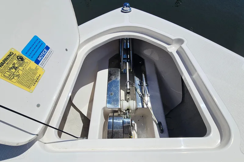 Slide: The Image of Anchor compartment of 2016 Pursuit DC 265 Dual Console boat, featuring safety labels. - 27