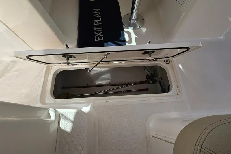 Slide: The Image of Open storage compartment on 2016 Pursuit DC 265 Dual Console boat deck. - 28