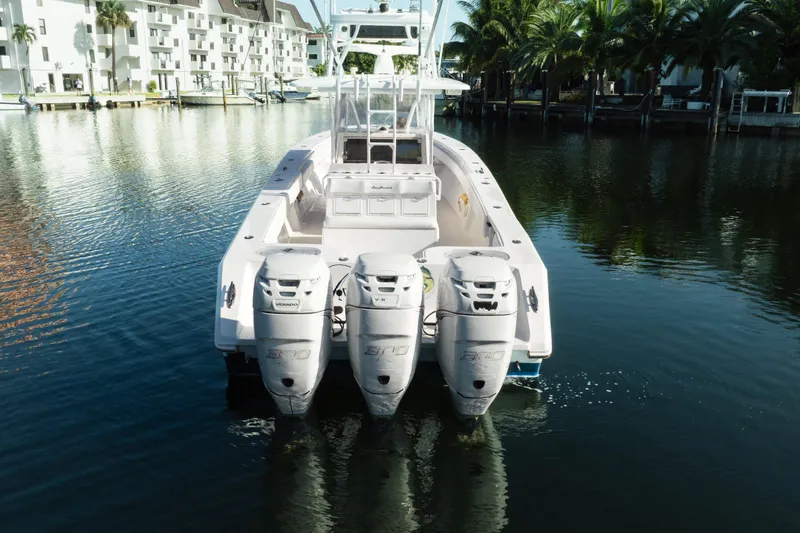 Slide: The Image of 2009 SeaHunter 40 boat with triple outboard engines docked in a serene marina. - 13