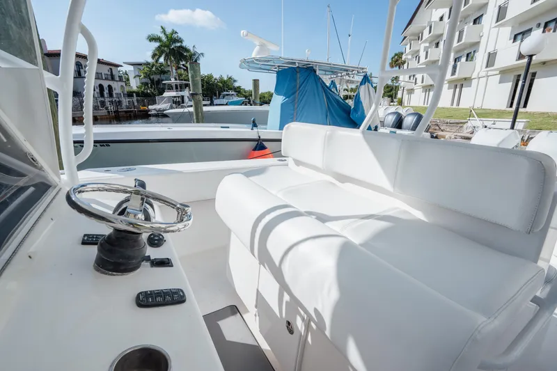 Slide: The Image of 2009 SeaHunter 40 boat interior with white seating and steering wheel, docked near waterfront buildings. - 18