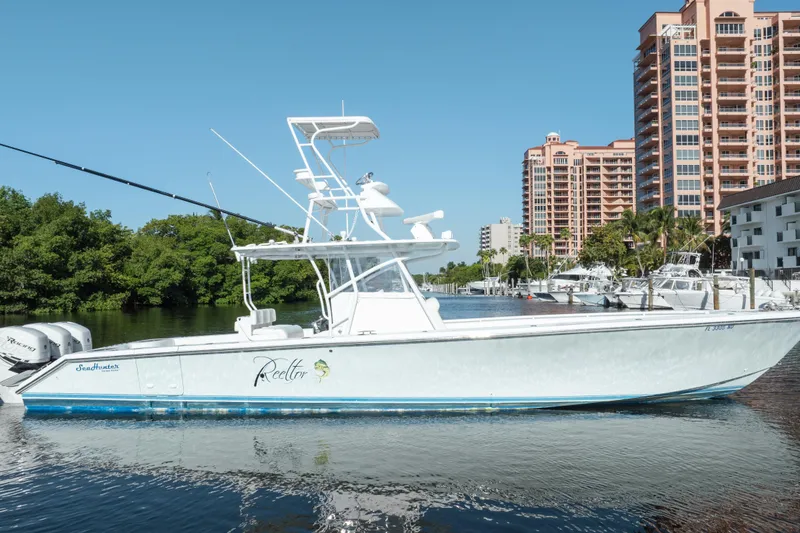 Slide: The Image of 2009 SeaHunter 40 boat docked near waterfront buildings and lush greenery. - 7