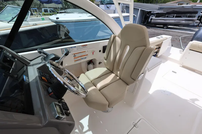 Slide: The Image of 2017 Pursuit DC 265 Dual Console boat interior with steering wheel and beige captain's seat. - 18