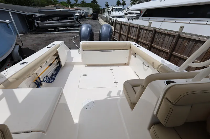 Slide: The Image of 2017 Pursuit DC 265 Dual Console boat interior with seating and storage, docked near yachts. - 22