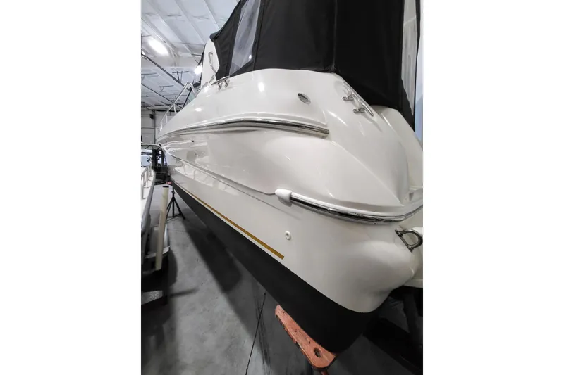 Slide: The Image of 2001 Sea Ray 310 Sundancer boat in storage, featuring sleek white hull and black cover. - 14
