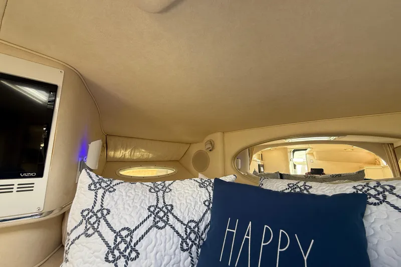 Slide: The Image of Interior of 2001 Sea Ray 310 Sundancer with cozy bedding and a "Happy" pillow. - 38
