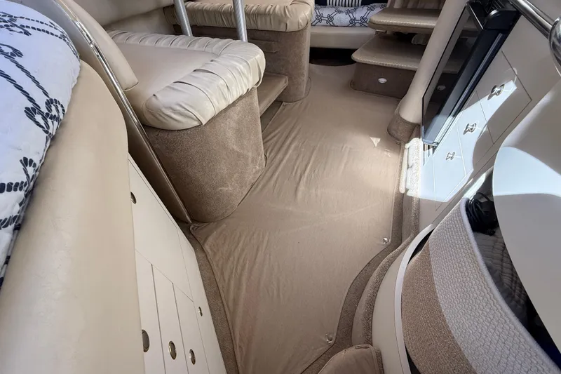 Slide: The Image of Interior of a 2001 Sea Ray 310 Sundancer boat, featuring beige seating and carpet. - 40
