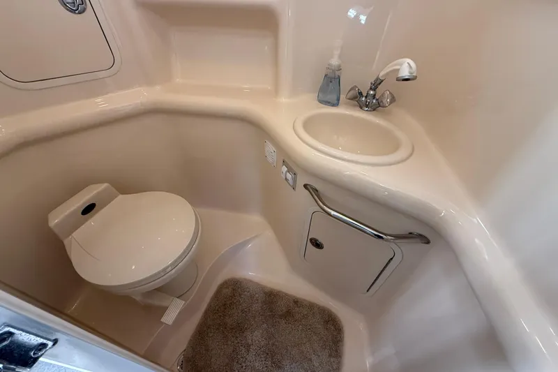 Slide: The Image of 2001 Sea Ray 310 Sundancer bathroom with toilet, sink, and storage cabinet. - 43