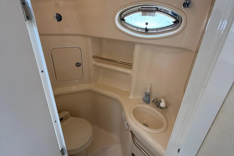 Slide: The Image of 2001 Sea Ray 310 Sundancer bathroom with sink, toilet, and porthole window. - 44