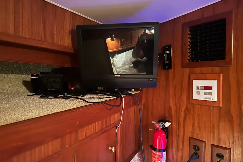 Slide: The Image of 1989 Egg Harbor 37 Convertible cabin interior with TV, clock, and fire extinguisher. - 19
