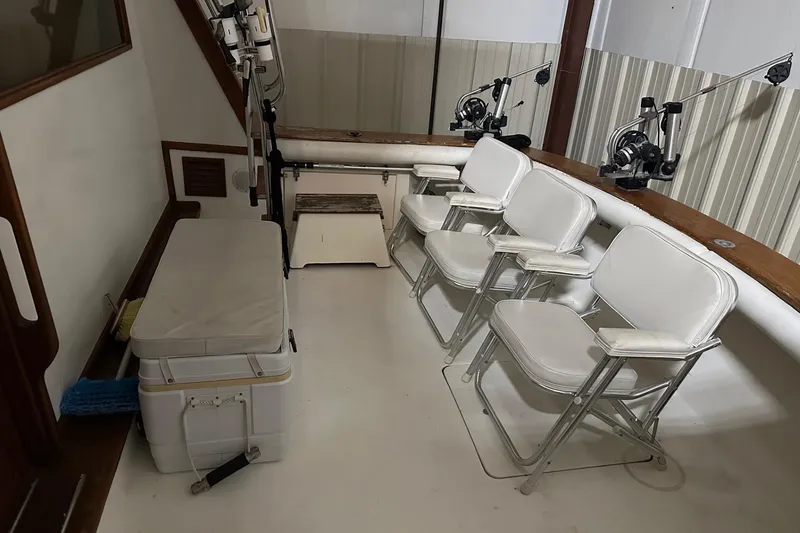 Slide: The Image of 1989 Egg Harbor 37 Convertible boat interior with white chairs and fishing rods. - 8