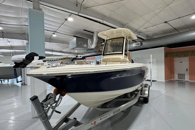 Slide: The Image of 2023 Scout 215 XSF boat on trailer in indoor showroom. - 2