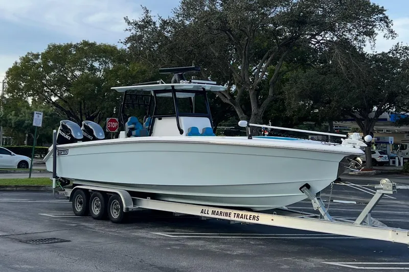 The Image of 2023 Sea Tech 33 CC boat on trailer in parking lot, surrounded by trees. - 0