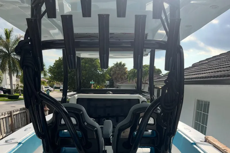 Slide: The Image of 2023 Sea Tech 33 CC boat interior with rod holders and seating, parked in a residential area. - 2