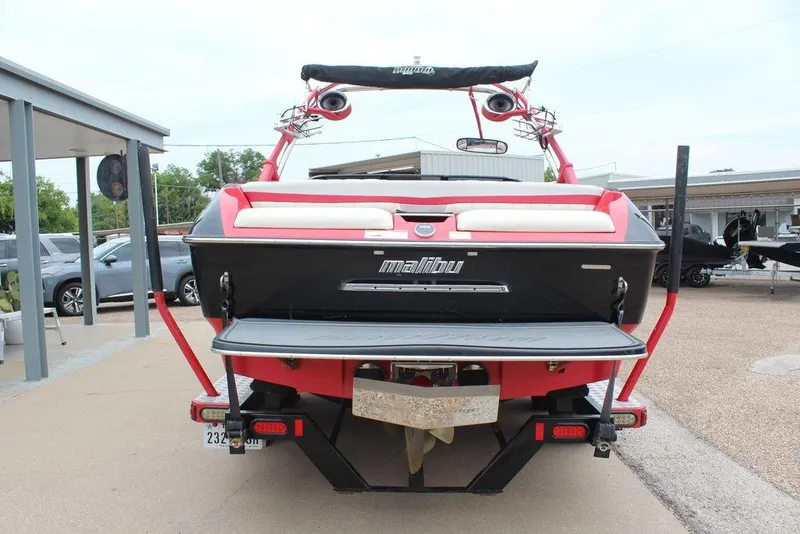 Slide: The Image of 2012 Malibu Wakesetter 22 MXZ boat, rear view, red and black design, parked outdoors. - 4