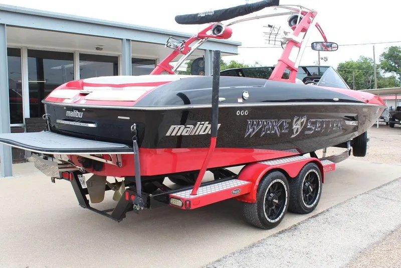 Slide: The Image of 2012 Malibu Wakesetter 22 MXZ boat on trailer, red and black design. - 7
