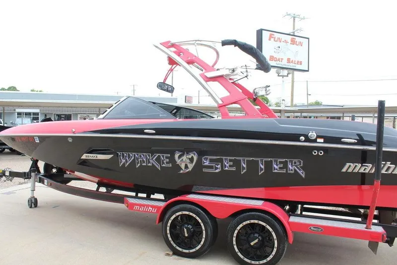 Slide: The Image of 2012 Malibu Wakesetter 22 MXZ boat in black and red at dealership. - 8