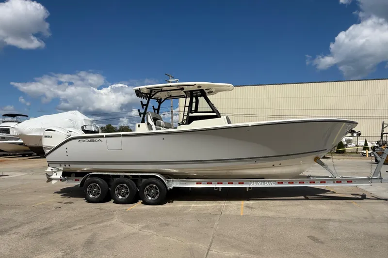 The Image of 2026 Cobia 305 Center Console boat on trailer under clear blue sky. - 0