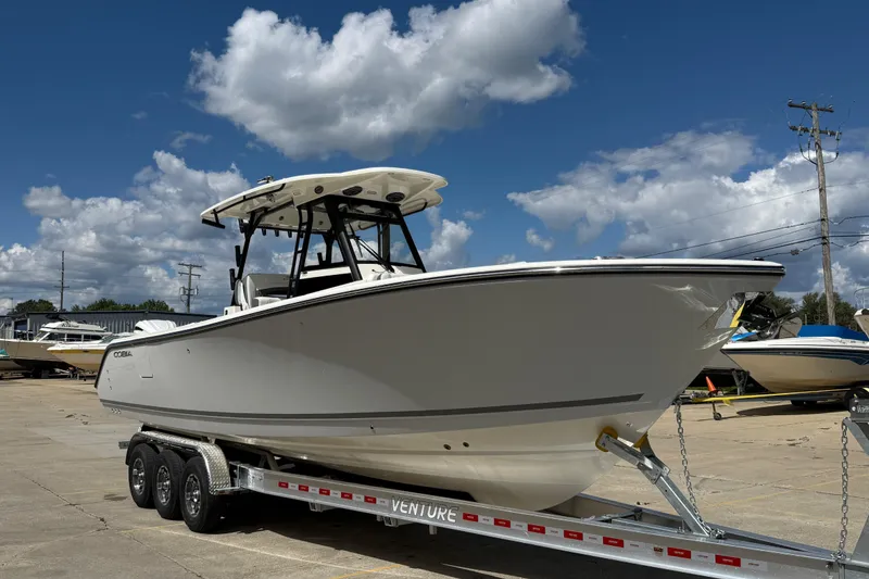 Slide: The Image of 2026 Cobia 305 Center Console boat on trailer under blue sky. - 1