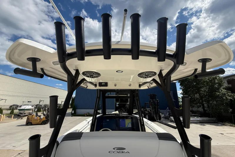 Slide: The Image of 2026 Cobia 305 Center Console boat with rod holders and speakers, docked under a cloudy sky. - 20