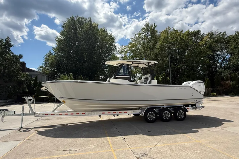 Slide: The Image of 2026 Cobia 305 Center Console boat on trailer, parked outdoors under cloudy sky. - 5
