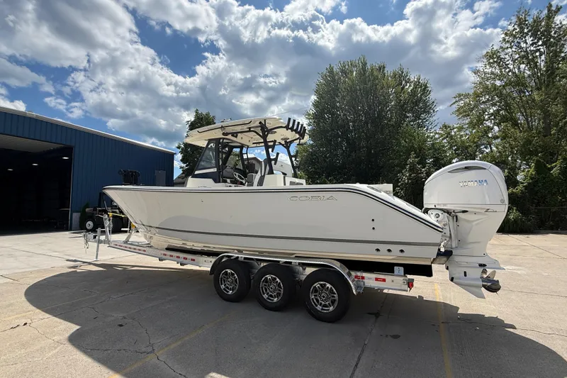 Slide: The Image of 2026 Cobia 305 Center Console boat on trailer, parked outdoors under a cloudy sky. - 6