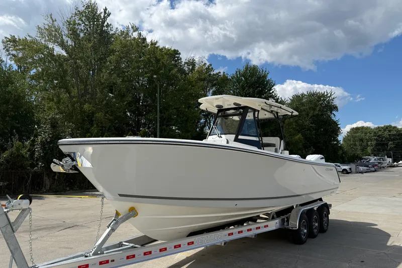 Slide: The Image of 2026 Cobia 305 Center Console boat on trailer, parked outdoors under cloudy sky. - 7