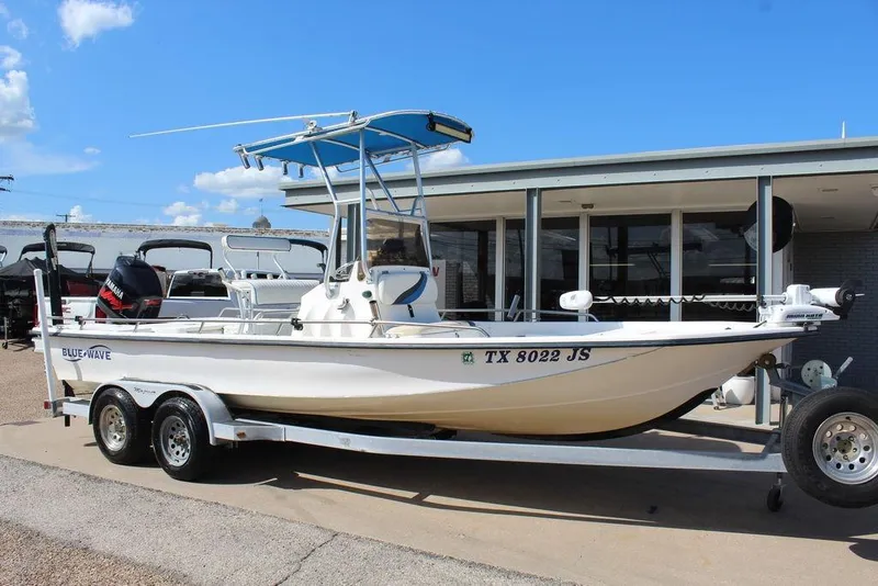 Slide: The Image of 2002 Blue Wave 2200 DELUXE CC boat on trailer, parked outdoors under clear sky. - 2