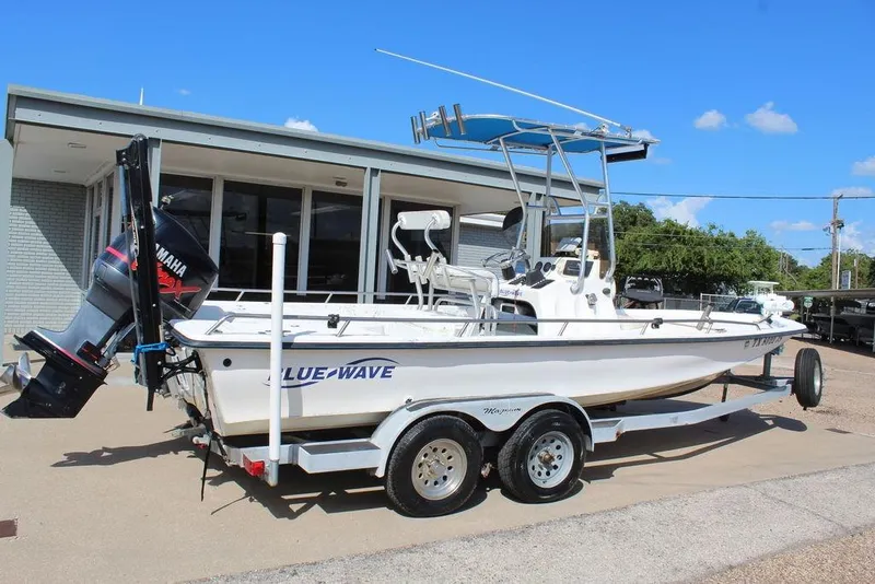 Slide: The Image of 2002 Blue Wave 2200 DELUXE CC boat on trailer, parked outdoors, with Yamaha outboard motor. - 5