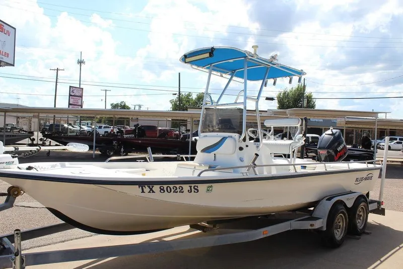 Slide: The Image of 2002 Blue Wave 2200 DELUXE CC boat on trailer, parked outdoors under a blue sky. - 6