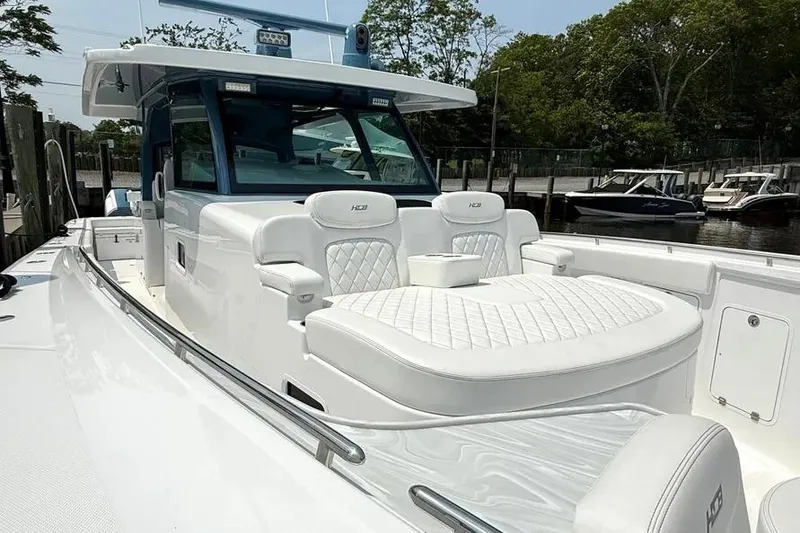 Slide: The Image of 2025 HCB 48 Campeon luxury boat with white seating and sleek design at a marina. - 13