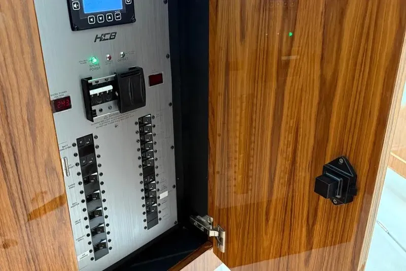 Slide: The Image of Electrical panel inside 2025 HCB 48 Campeon boat with wood finish door. - 69