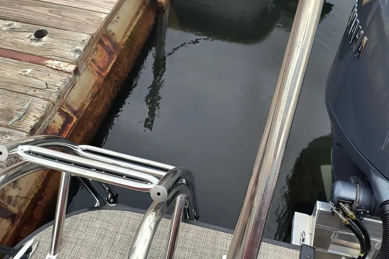 Slide: The Image of 2025 SunCatcher Fusion 324RC boat docked, showing motor and metal railing. - 13