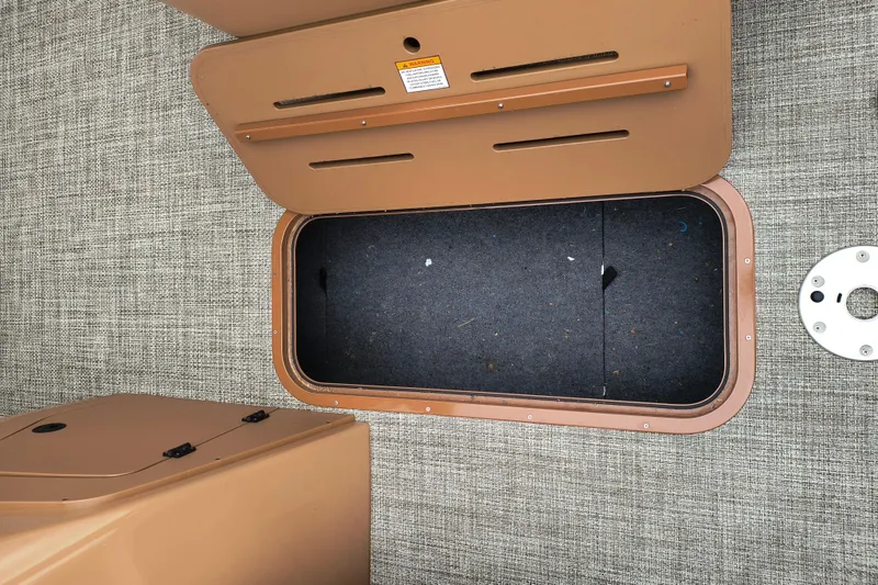 Slide: The Image of Open storage compartment on 2025 SunCatcher Fusion 324RC boat, featuring carpeted interior. - 6