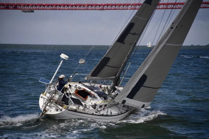 The Image of Sailing yacht Tartan 41 from 1972 navigating under a red bridge on open water. - 1