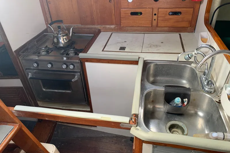 Slide: The Image of 1972 Tartan 41 yacht kitchen with stove, sink, and wooden cabinetry. - 52