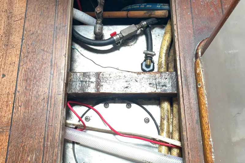 Slide: The Image of 1972 Tartan 41 boat interior showing wooden flooring and visible plumbing components. - 66