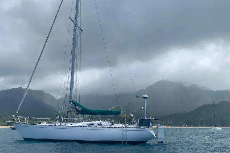 Slide: The Image of Sailboat Tartan 41 (1972) anchored with mountainous backdrop under cloudy skies. - 7