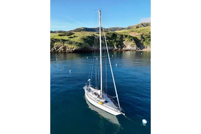 Slide: The Image of Sailboat Tartan 41 (1972) anchored in scenic bay with lush hills in background. - 80