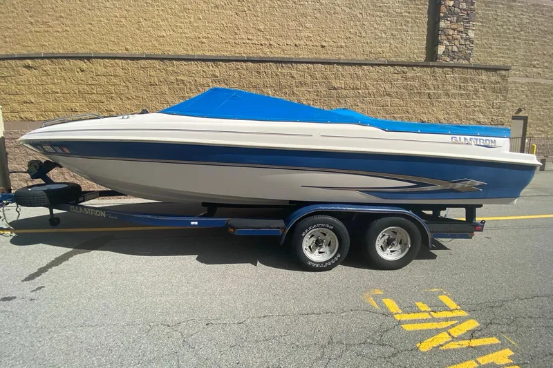 Slide: The Image of 1998 Glastron/Carlson GS225 boat on trailer with blue cover, parked outdoors. - 0