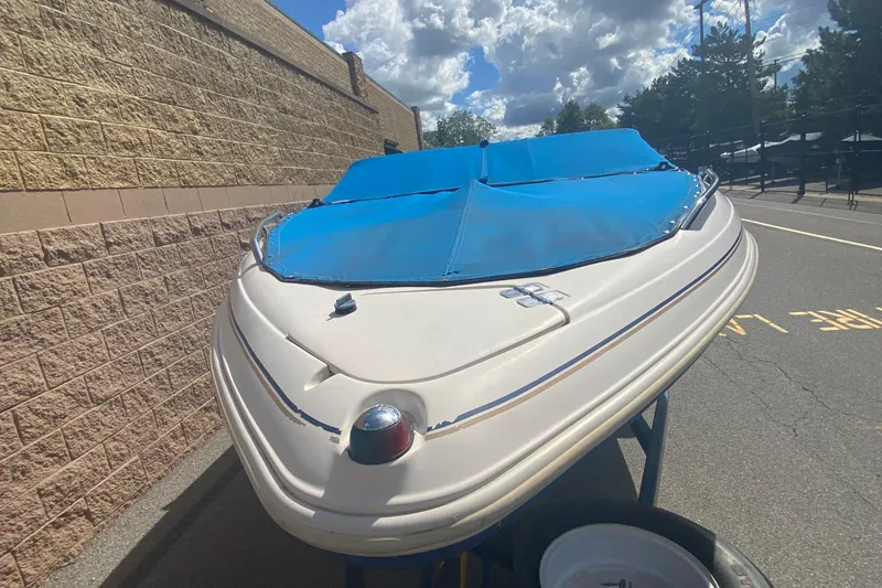 Slide: The Image of 1998 Glastron/Carlson GS225 boat with blue cover, parked outdoors on a sunny day. - 4