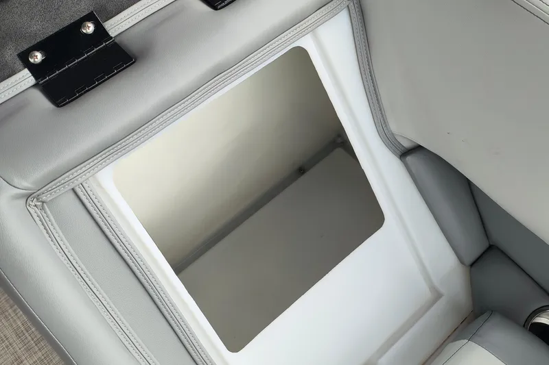 Slide: The Image of SunCatcher Select 324RC 2025 boat storage compartment with gray upholstery and open lid. - 24