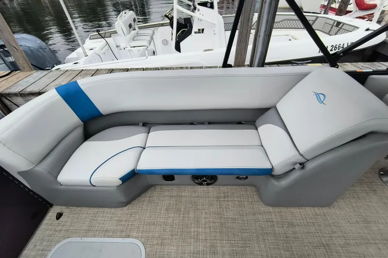 Slide: The Image of 2025 SunCatcher Select 324RC boat interior with gray and blue seating, docked by the water. - 29
