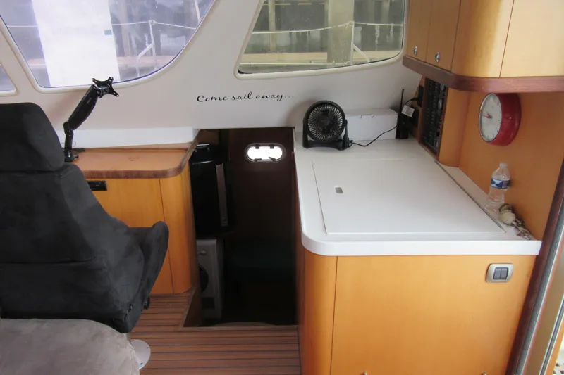 Slide: The Image of Interior of 2001 Catana 471 sailboat with navigation station and seating area. - 100