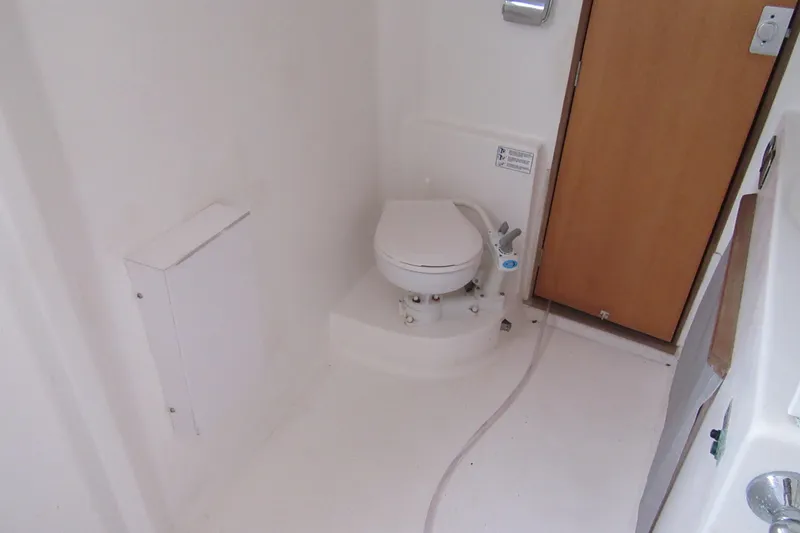 Slide: The Image of Compact marine bathroom in 2001 Catana 471 yacht, featuring a white toilet and wooden door. - 125