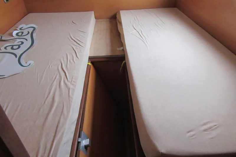 Slide: The Image of Twin beds in a 2001 Catana 471 catamaran cabin, featuring simple bedding. - 140