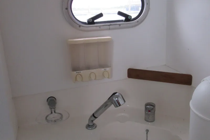 Slide: The Image of Bathroom sink area on a 2001 Catana 471 yacht with dispenser and porthole. - 149
